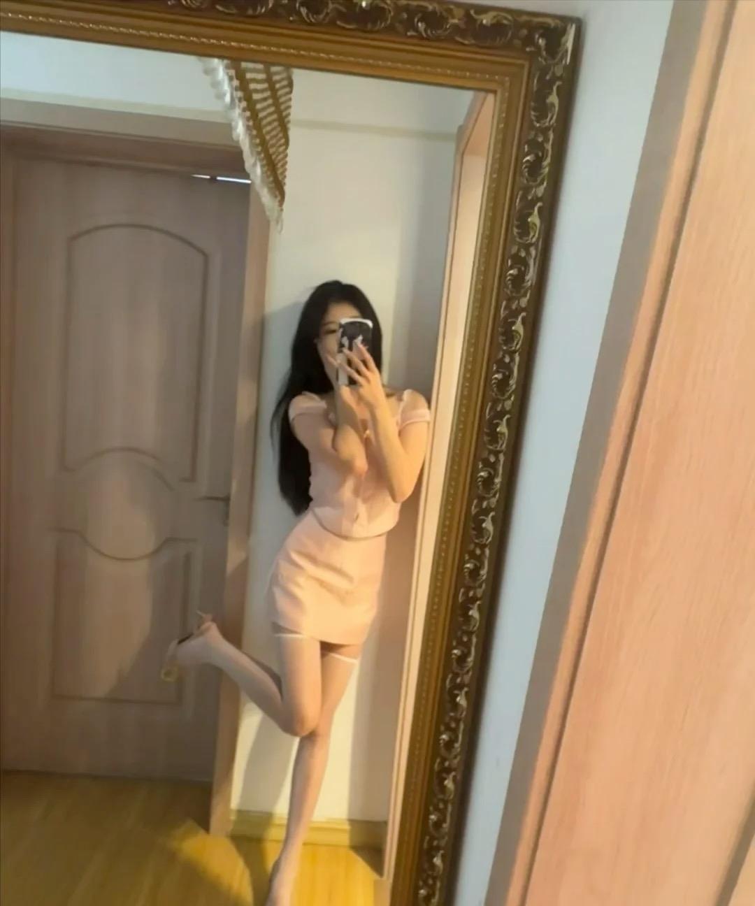 自拍时，她靠在门边，穿着粉色裙。