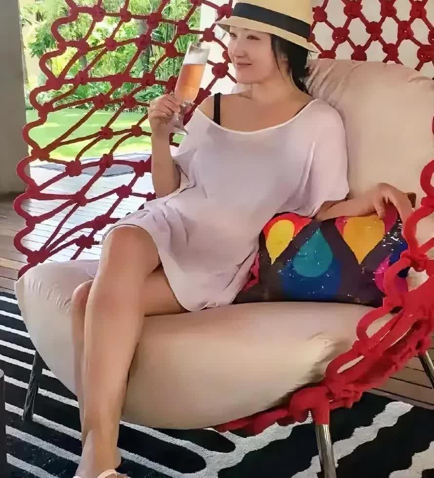 54岁杨钰莹，一袭透视连衣裙搭配粉红色鞋底人字拖，头戴白色礼帽，一眼看过去满满的