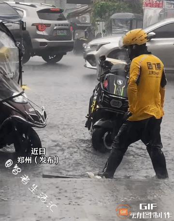 河南，一名外卖小哥站在大雨中，脚踩“缓冲石”帮骑手们上台阶，然而他衣服鞋袜全都湿