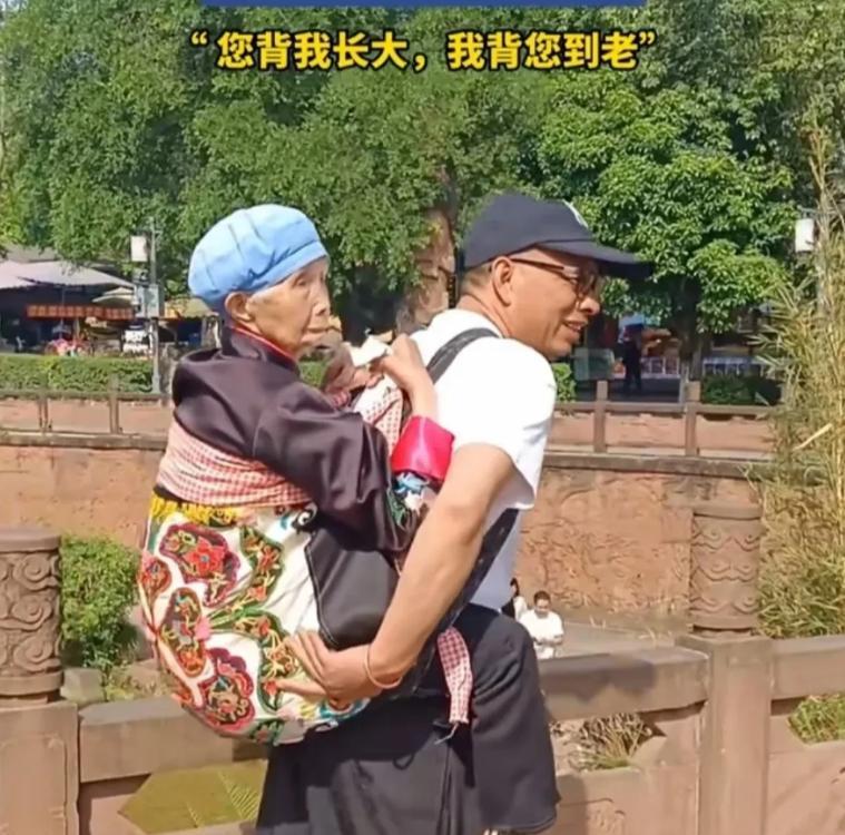 看哭了！四川黄龙溪景区的人流中，有一对母子引人注目。一位头发花白的大叔，用背带把
