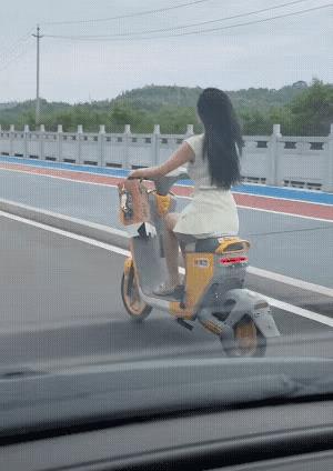 美女，你的月饼。
公路上，一位美女骑着电驴。车把手上原本拄着一盒月饼，不过月饼已