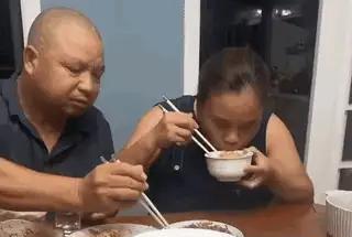 一女子在饭桌上吃的狼吞虎咽，一手端碗，一手拿着筷子一秒钟都不带停下的，好像饿了八