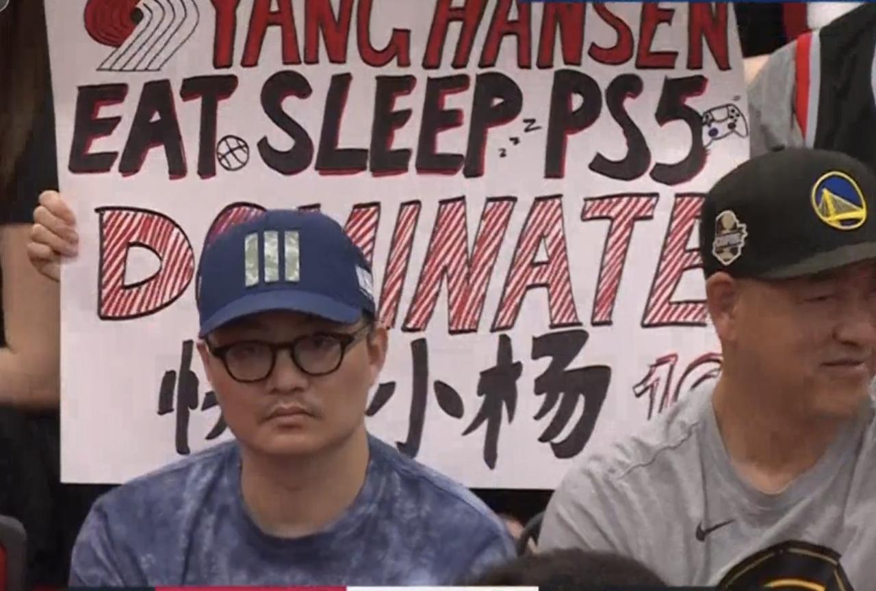 “快乐小杨”牌子前面，这位大哥的表情亮了
昨天开拓者102-83战胜火箭，杨瀚森