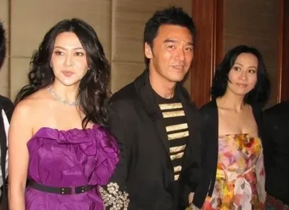 钟镇涛好幸福，手牵两位美女，左边关之琳，右边刘嘉玲。
关之琳身穿紫色裙，虽然上了