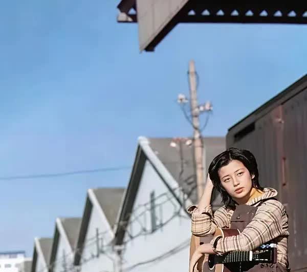 这是当年山口百惠在日本的铁路边坐在路基上休息，那时候上口百惠好清瘦，怀中还抱着一