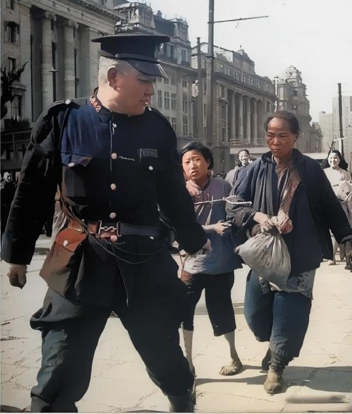 1948年上海，两名警员押解衣衫褴褛的母女，围观者嬉笑。旧社会