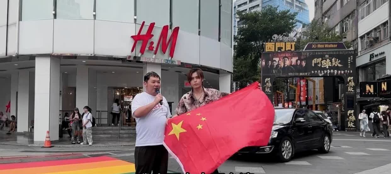 田中裕之和另一名日籍男子在台北闹市区的西门町举着中国国旗，手持麦克风，用汉语和日