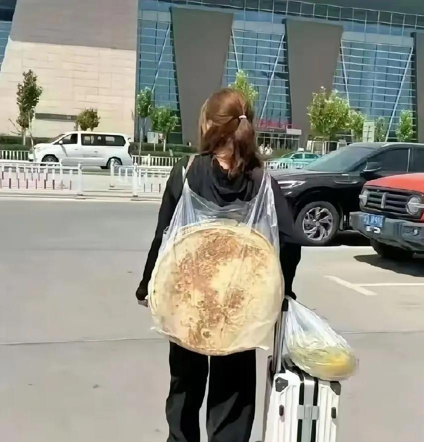 上人民日报了，她背着大饼走出深圳机场的画面得到官方认可了！画面中这个背着几个大饼