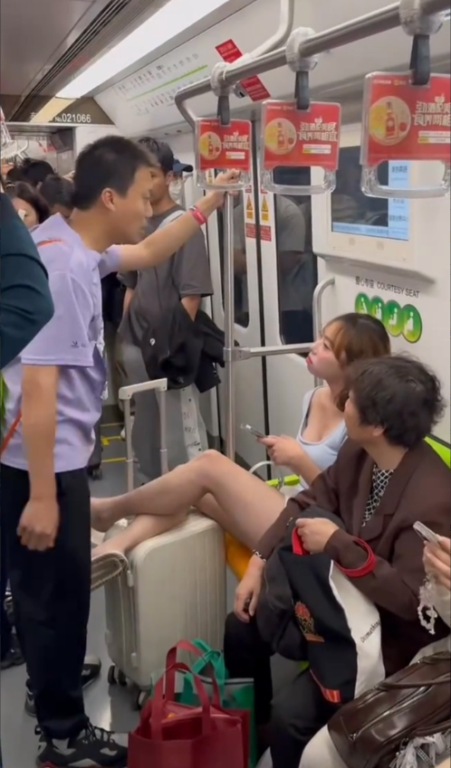 上海地铁，女子将腿翘在行李箱上，影响他人通行，一位男乘客劝导其放下，女子非但不听