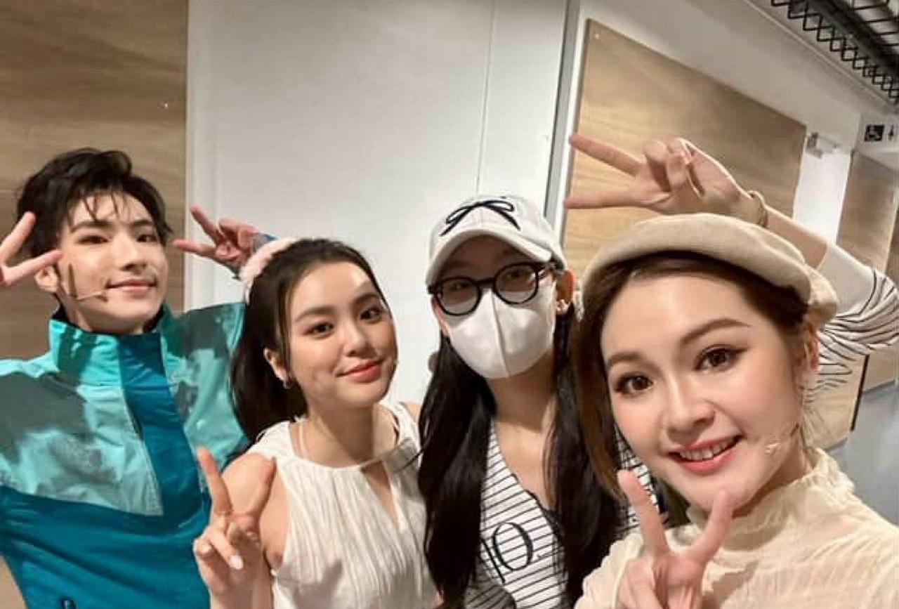 身穿横间上衣衬灰色运动裤的Gigi，头戴白帽加口罩及黑色粗框眼镜的她，小，背着大