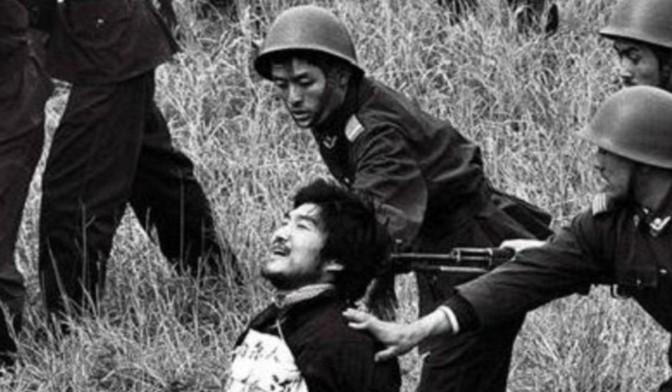 1990年，枪决西北悍匪魏振海的现场，照片中魏振海被五花大绑地跪在草丛中，一把上