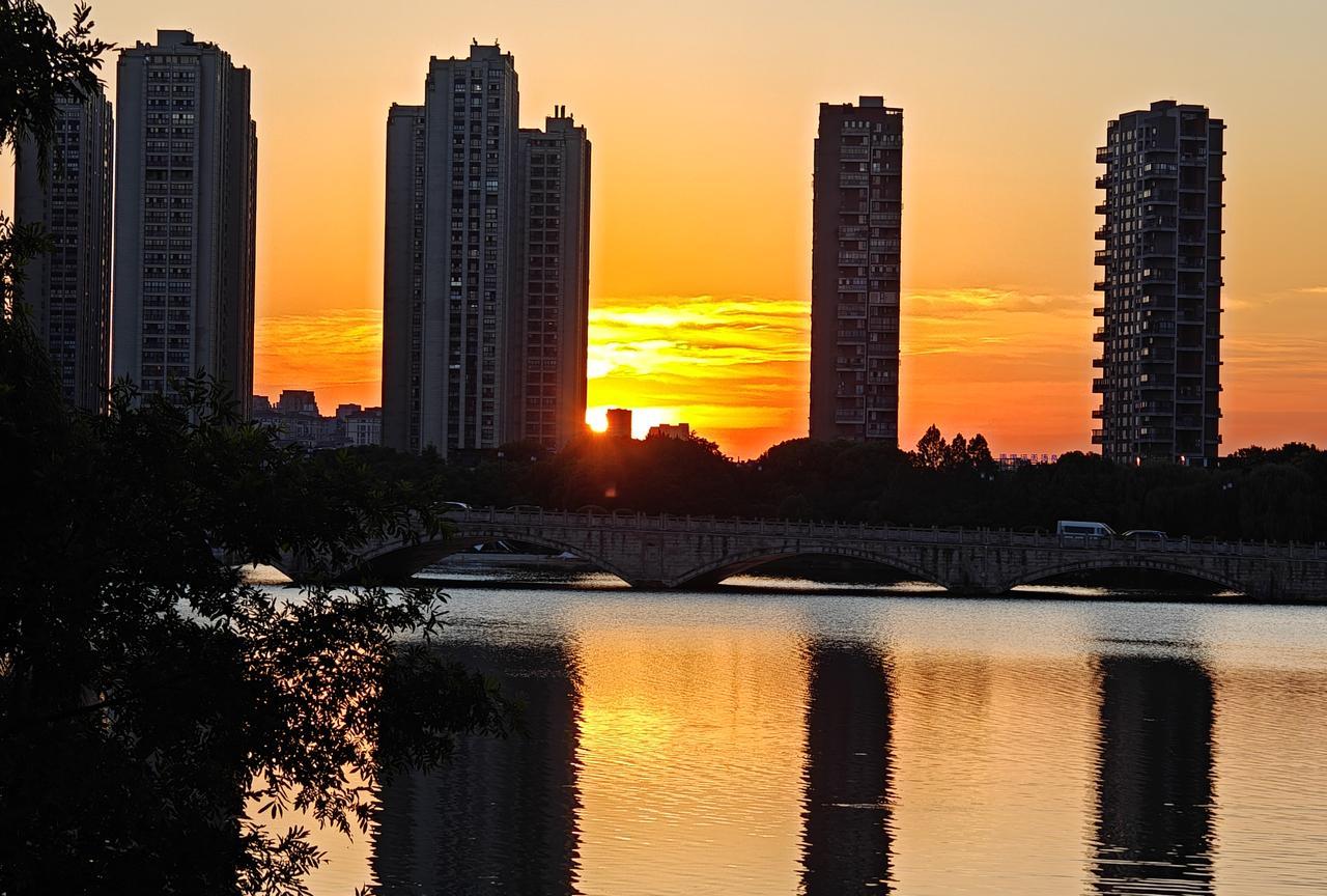 夕阳西下，城市倒映在湖面上。也只有自己坐车回家，才能看到傍晚时分的美景。#晒图笔