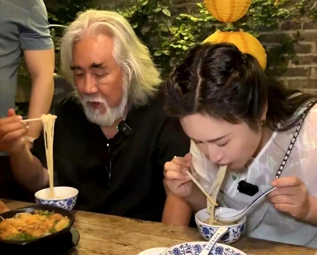 74岁张纪中在夜市吃东西，妻子杜星霖把脸涂得好白，两口子坐在路边小桌子上面品尝美