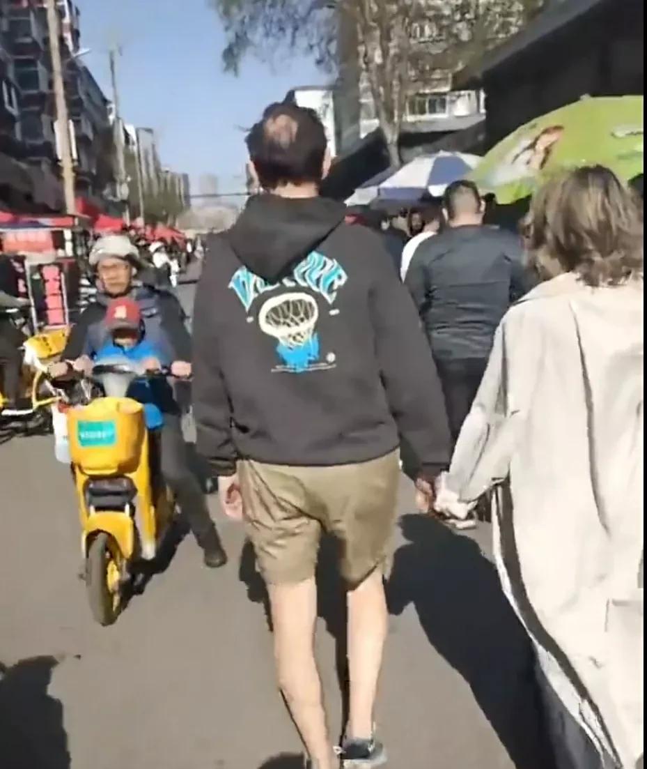 乌戈洛佩斯和妻子手牵手走在沈阳街头，这乌戈小老头这么早就开始穿短裤了？有那么热吗