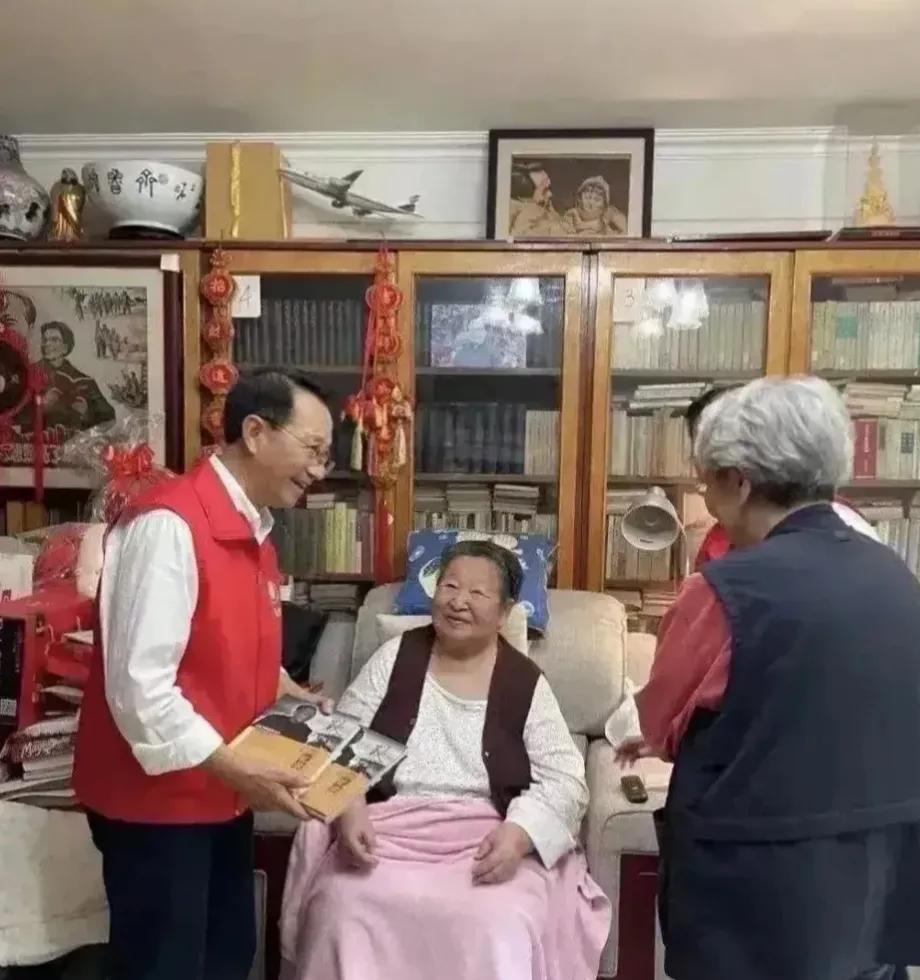 李讷坐在沙发，同事们前来看望，亲切交谈，嘘寒问暖，笑容满面，合影留念，永恒的回忆