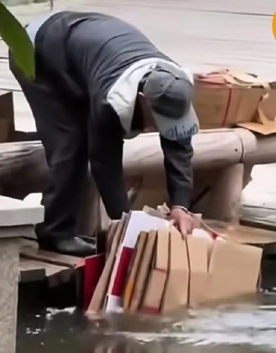 一个拾荒老人把自己捡的一大捆纸箱片小心翼翼地放到水里边，等短短的时间浸满水以后，