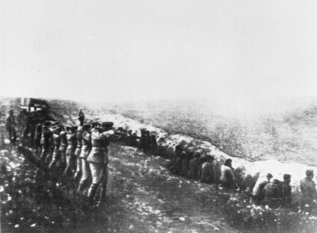 1942年，乌克兰基辅 ,，德国行刑队在乱葬坑旁向乌克兰老百姓开枪。 。
