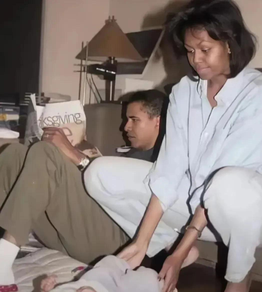 这张照片拍摄于1998年，奥巴马躺着看报纸，米歇尔在逗出生才几个月的女儿玩。
两