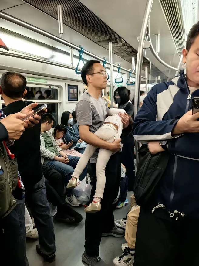 一位网友上班途中，在地铁上看到这样一幕：一位男士抱着熟睡的女儿，汗流浃背地站在车