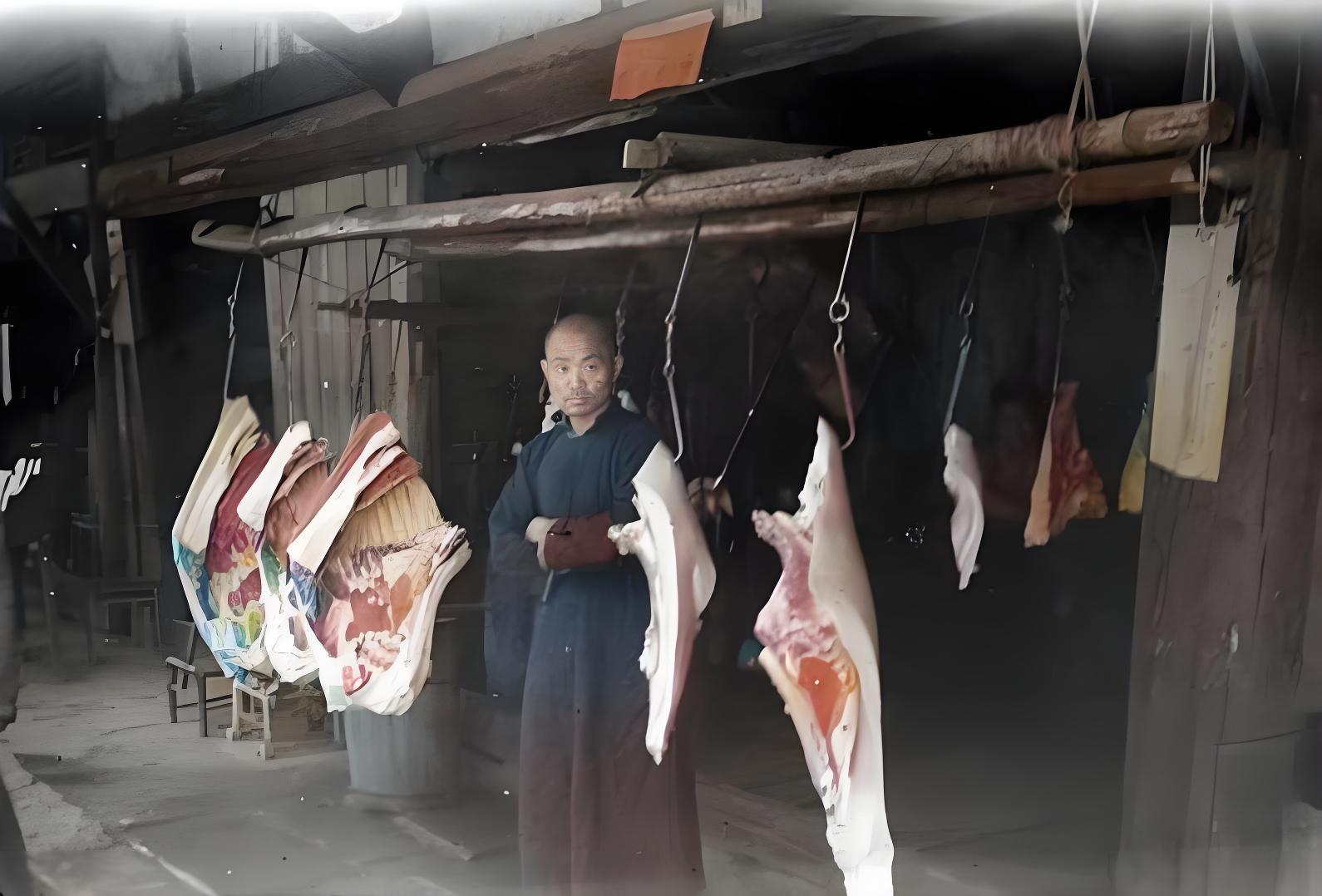 这是一张反映旧中国市井生活的黑白照片，画面中展示的是一家传统肉铺的场景。一位身着