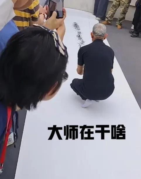 射墨作画，只见一大师在众人围观下，手拿几个注射器对着白纸喷墨，动作行云流水，激情