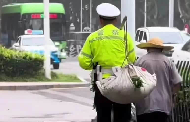 近日，安徽淮南，街上一卖菜老人因扁担太重而步履蹒跚，现场执勤的交警主动上前，帮助
