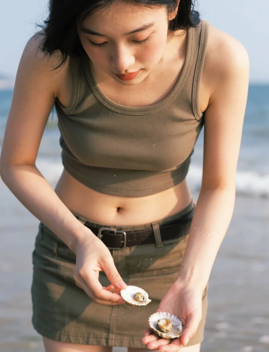 拾贝途中的亚洲美女，被手中的贝壳吸引