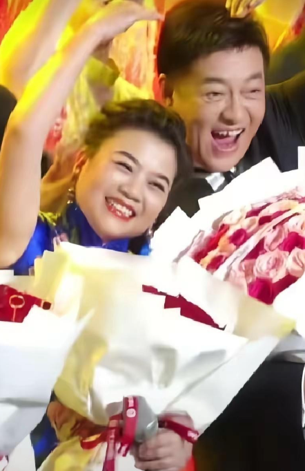 张也、吕继宏两个人手捧着鲜花，比着爱心，在舞台上笑的脸都要开花了。

张也长相端