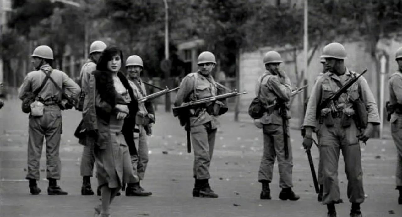 这是1978年的某一天，革命前夜的伊朗街头，士兵们在维持秩序。这位女士可能是一位
