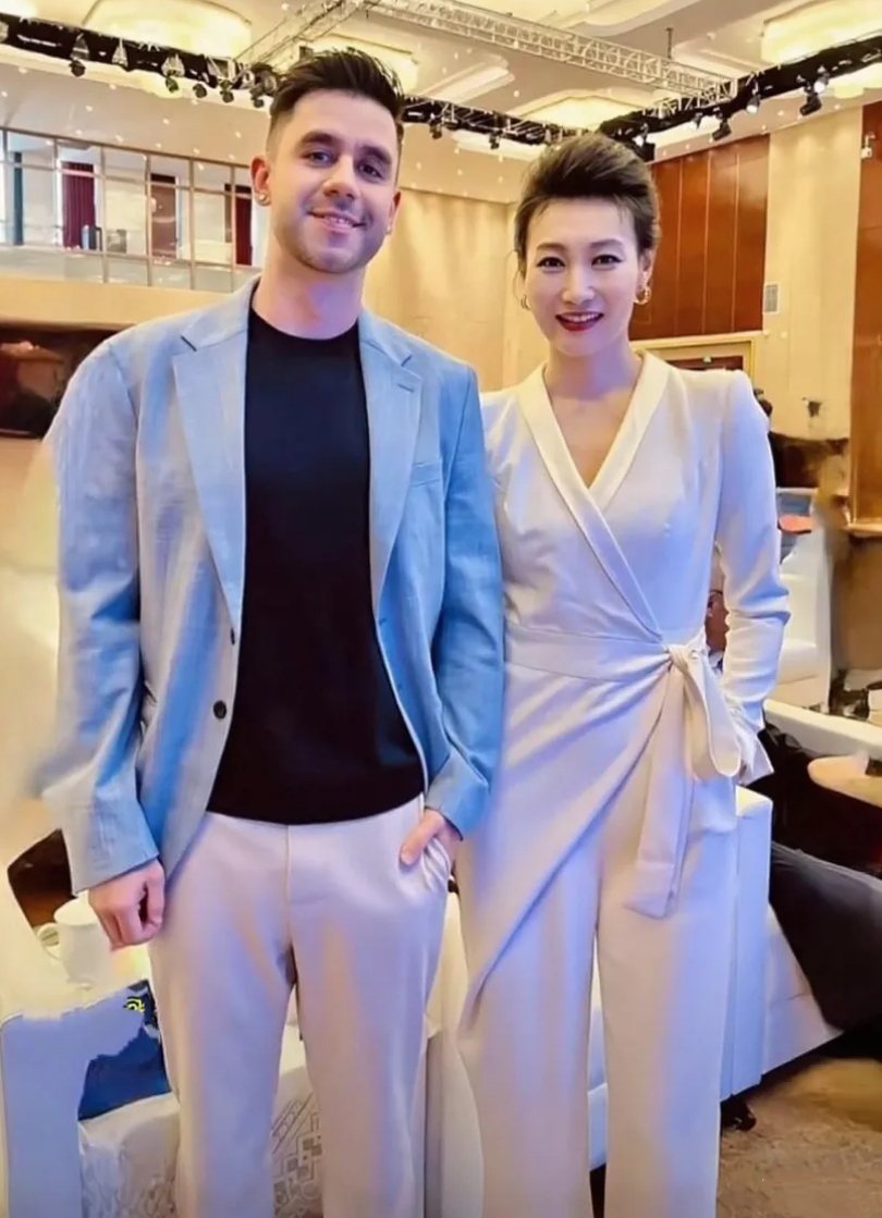 央视主持李梓萌和老外合影，双方的肢体语言、服装搭配和互动自然度，感觉好般配。作为