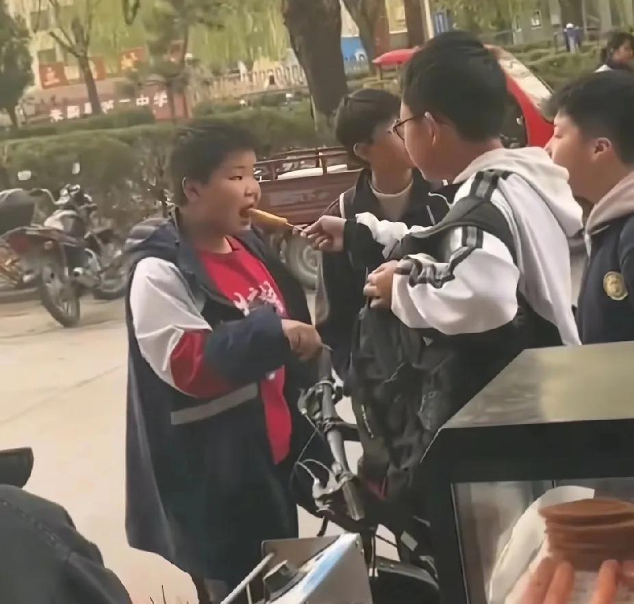 校园旁的烤串摊前，一个学生男孩买了一根烤肠，接下来看到的画面，让人直呼感动暖心了