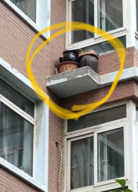 女子在小区里散步时，无意间抬头一看，发现四楼住户竟将闲置的陶土坛子放在了空调外机的平台上