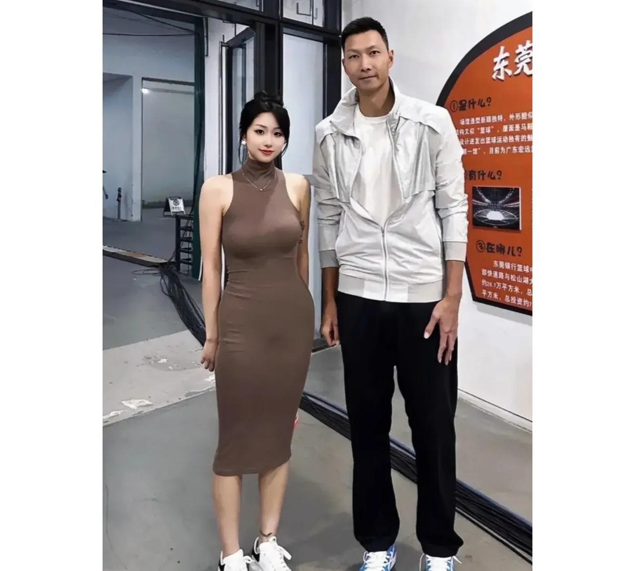一代篮球巨星易建联与年轻貌美的女球迷早期在东莞的合影，女球迷五官秀丽，身着棕色高