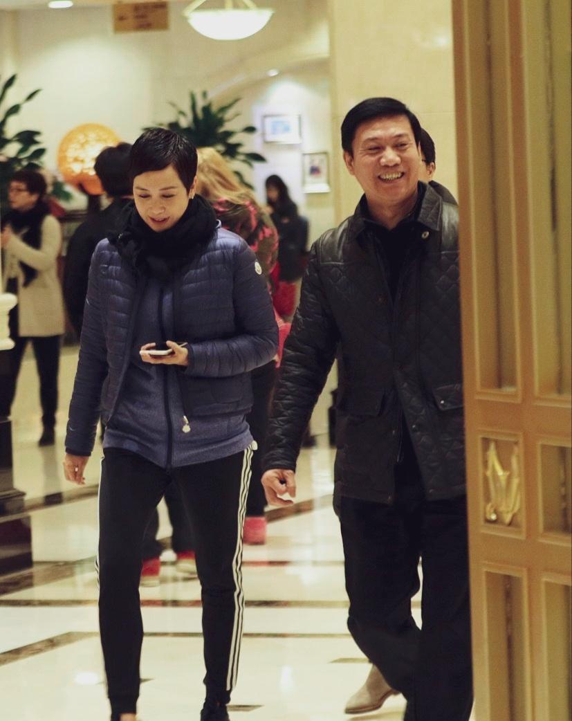 蒋雯丽近照蓝色羽绒服配黑色运动裤，短发造型，手拿手机，低头走路，面带微笑。看着很