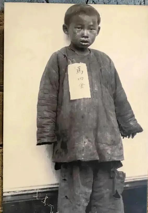 晚清被拐儿童"马四金"胸前挂牌留影，稚嫩脸庞令人揪心。《大清律例》规定拐卖者斩立