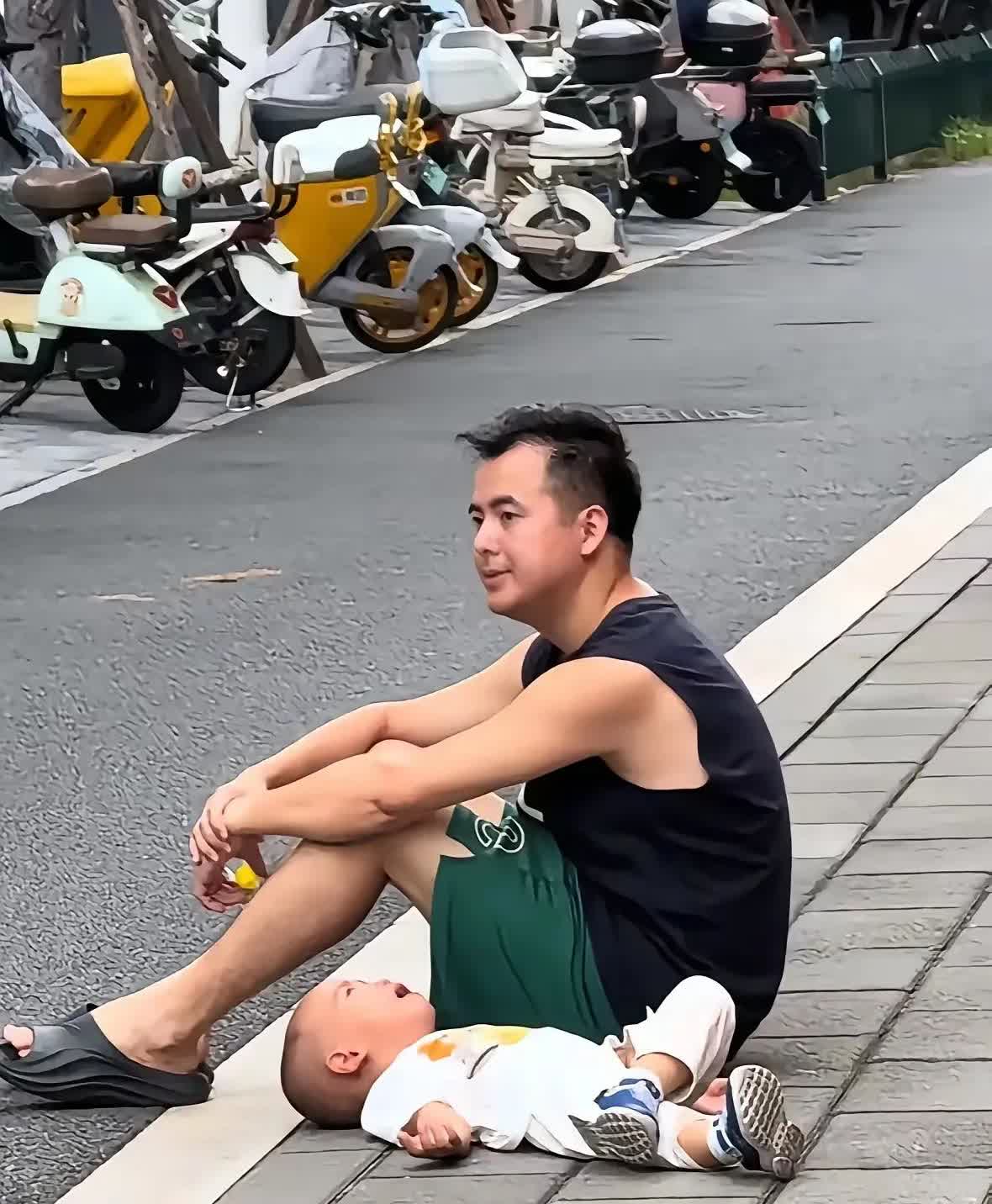 图片中这位男子，周末带着未满周岁的孩子出去玩，感觉自己带孩子特别的累了，每一分钟