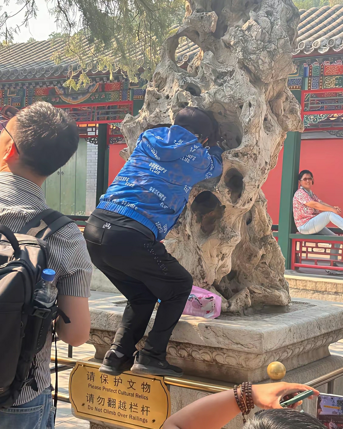 颐和园，虽然栏杆上有提示牌但这个游客可能不认识字，隔着假山石给坐在长廊的女士拍照