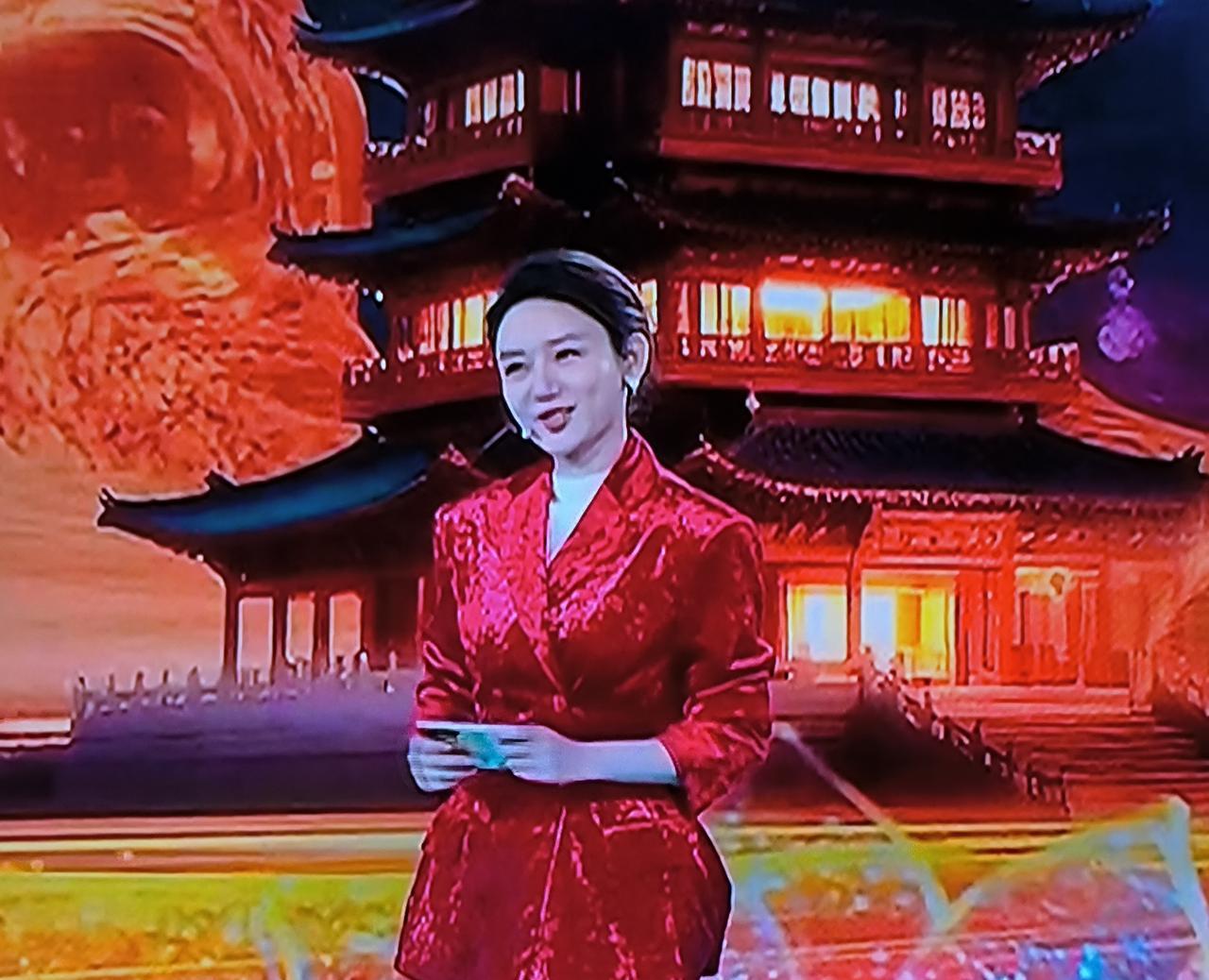 一身大红色的丝绒西服套装，太闪太亮，耀眼的没法看，里边还搭个白色秋衣拥到脖子根，