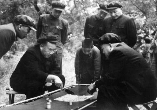 1953年，排名前两位的元帅在棋盘上相持不下，邓公在一旁静静观战。
