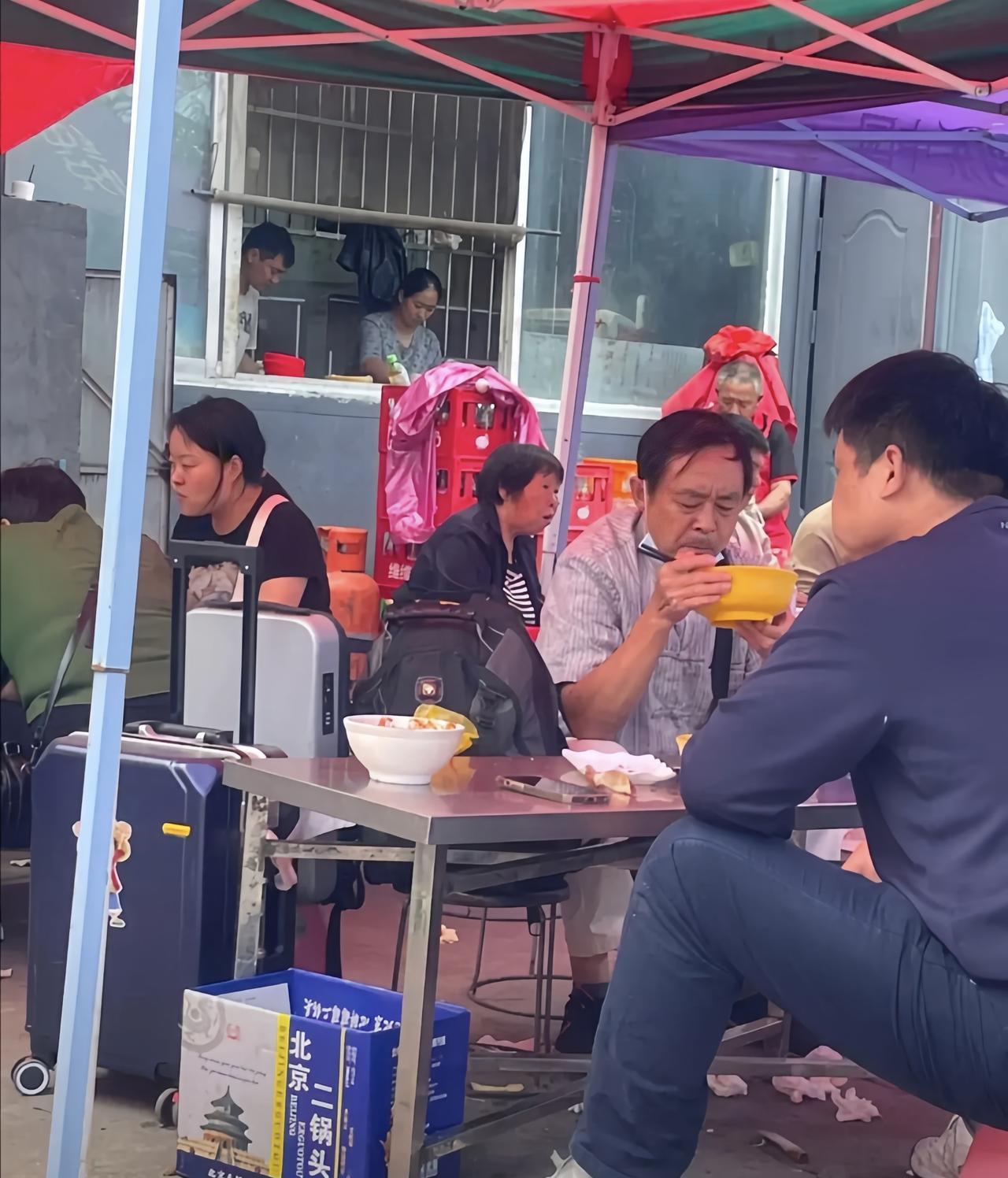 看对面大爷深沉地表情，一只手端着碗底，一只手捧着碗边吃饭，不好惹的样子。
和大爷