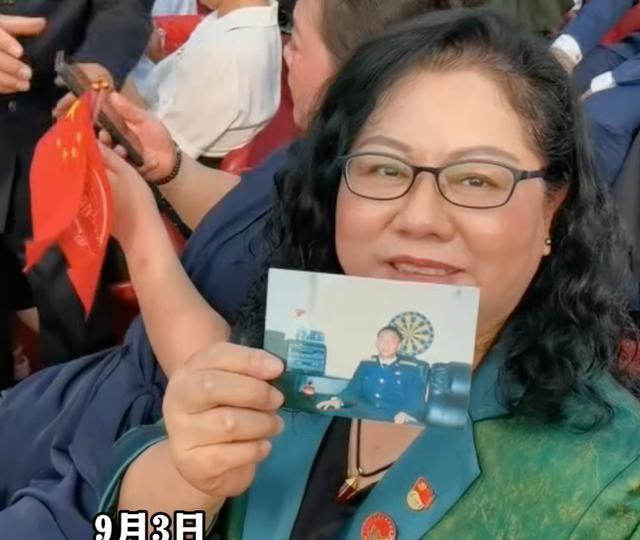 “海空卫士”王伟遗孀阮国琴带着王伟照片，在北京天安门广场观看阅兵。她说，王伟，我