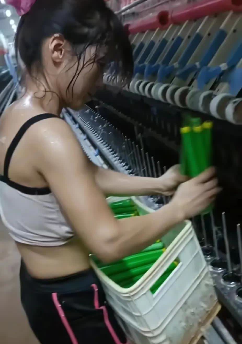 纺纱车间里，一名干活的女子正在动作麻利地干活，看见女子的衣服和头发，瞬间令人心疼