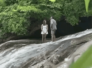 ​为追求浪漫惊喜的效果，男生求婚仪式​选择在小溪中

男生掏戒指下硊​，脚一