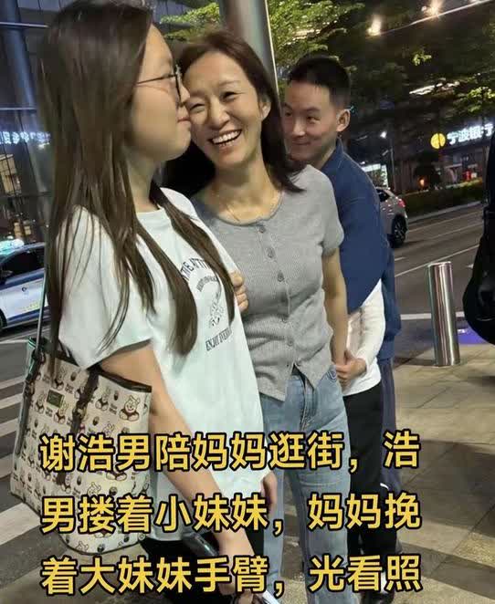 谢浩男和妈妈一起去逛街，他一手搂着小妹，而妈妈则挽着大妹的手臂，光看这画面就让人