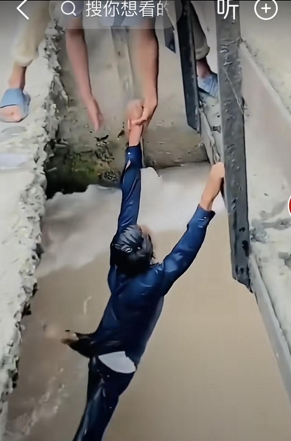 照片中落水者一开始自己抓住了建筑物，但后来见到有人施救便松手了，把手交给了施救者