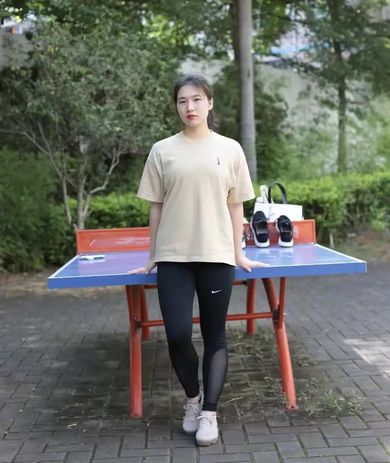 女孩站在乒乓球桌前，准备打球。
