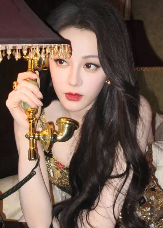迪丽热巴身穿鎏金闪片吊带裙光彩照人，手持金色电话，复古风十足！