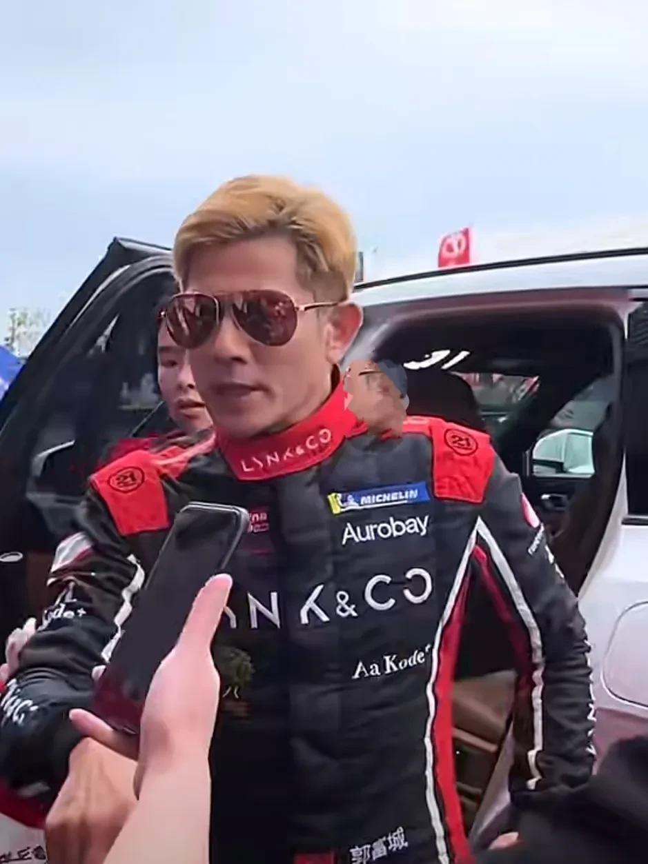郭富城一身给红色骑行服亮相，真的又飒爽又帅气，黄色的头发整齐干净，茶色眼镜，五官