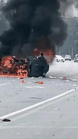 事发广东韶关，两车相撞引发大火，司机被困车内动弹不得。
路过小哥伸出援手，忍着剧