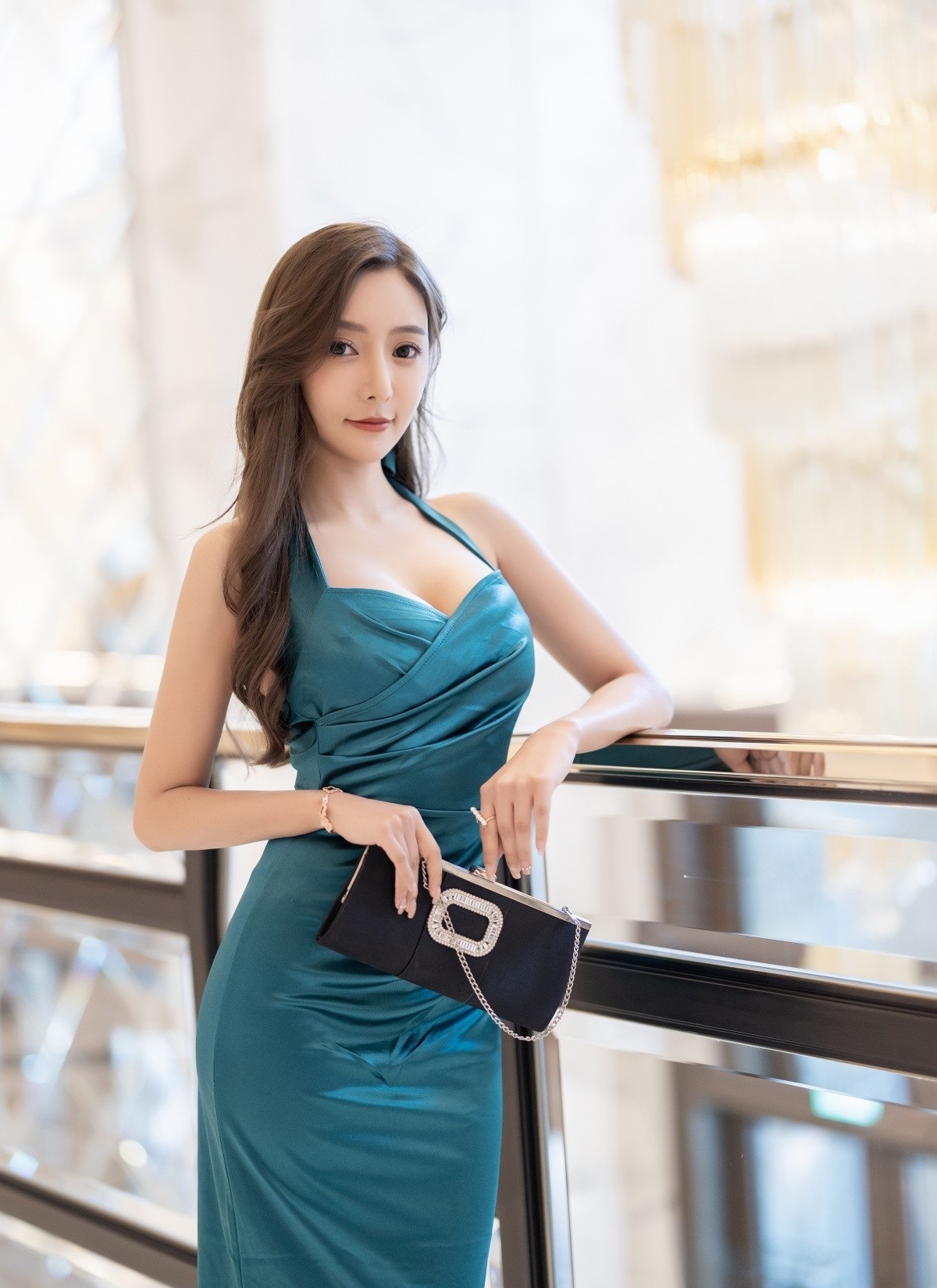 孔雀蓝缎面吊带裙，配上同色细跟高跟鞋，展现玲珑有致的身材线条